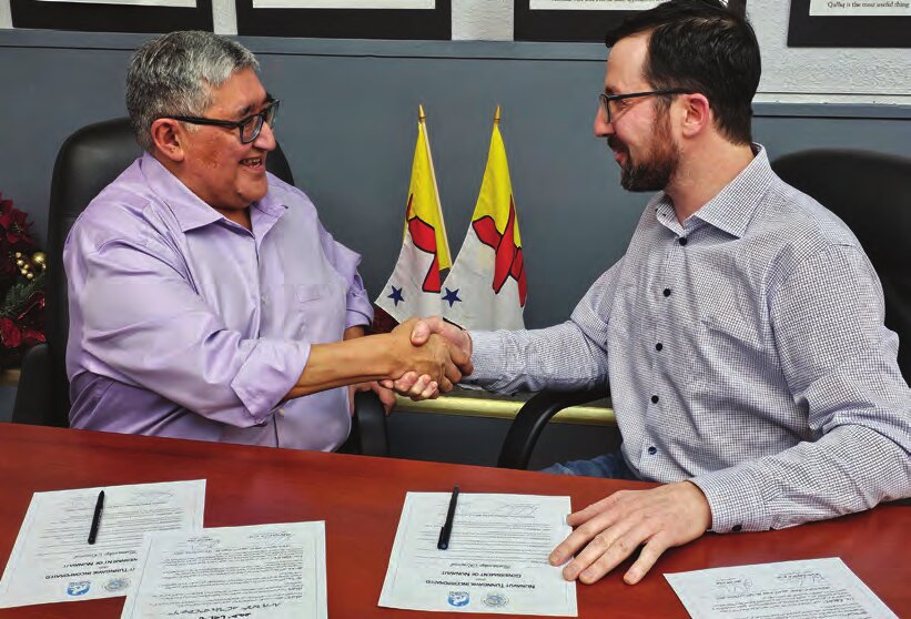Premier of Nunavut and NTI President shaking hands after signing an agreement.